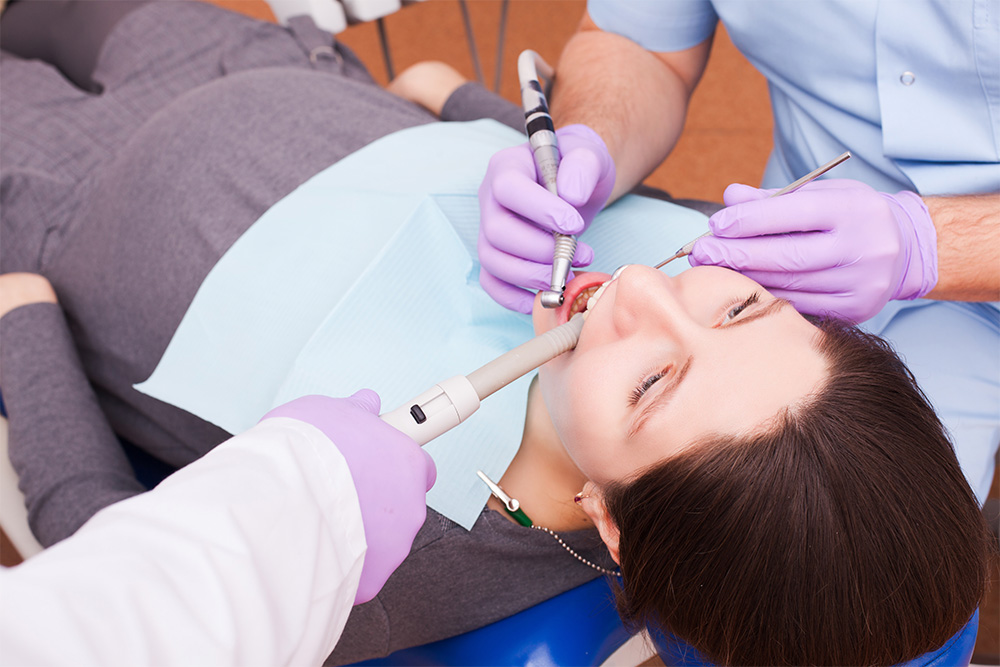 Behandlung von Zahnfleischbluten in der Schwangerschaft dargestellt durch eine schwangere Frau auf einem Zahnarztstuhl